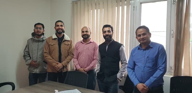 Samir with four colleagues in a meeting room